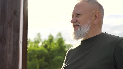 a bearded man having a drink outdoors