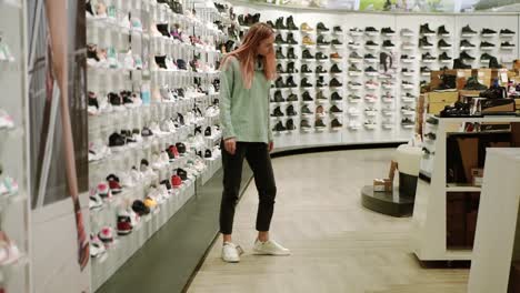 woman fits new white sneakers in shoe store, looking at the mirror