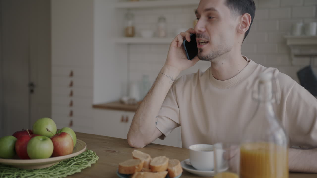 Man Having Breakfast and Talking on Phone
