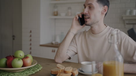 man having breakfast and talking on phone
