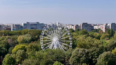 aerial view of a white ferris wheel in oraselul copiilor park with bucharest's colorful cityscape in the background, romania