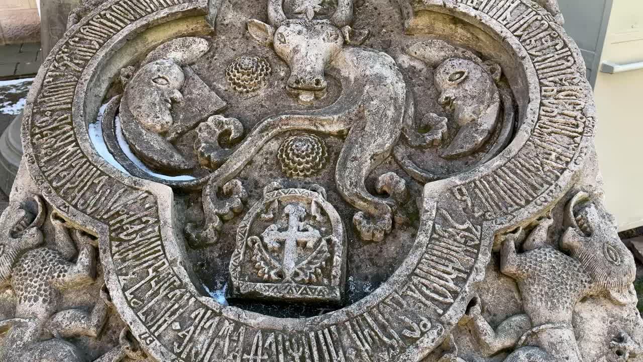 Stone-carved Moldavian coat of arms featuring an aurochs, cross, and inscriptions.