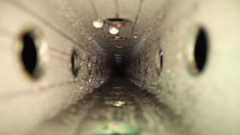 static shot of a wet zinc-plated steel perforated square tube with a wide angle macro probe lens - rolling the focus from one end to the other