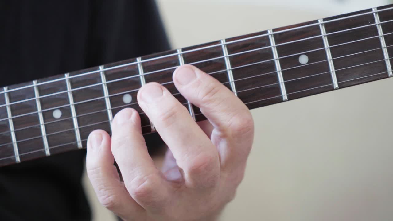 Close-up of a guitarist's left hand improvising on an electric guitar