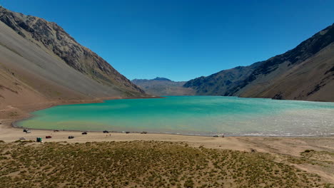car driving near vibrant blue water and arid mountains in chile’s cajon del maipo region, visiting stunning desert lake