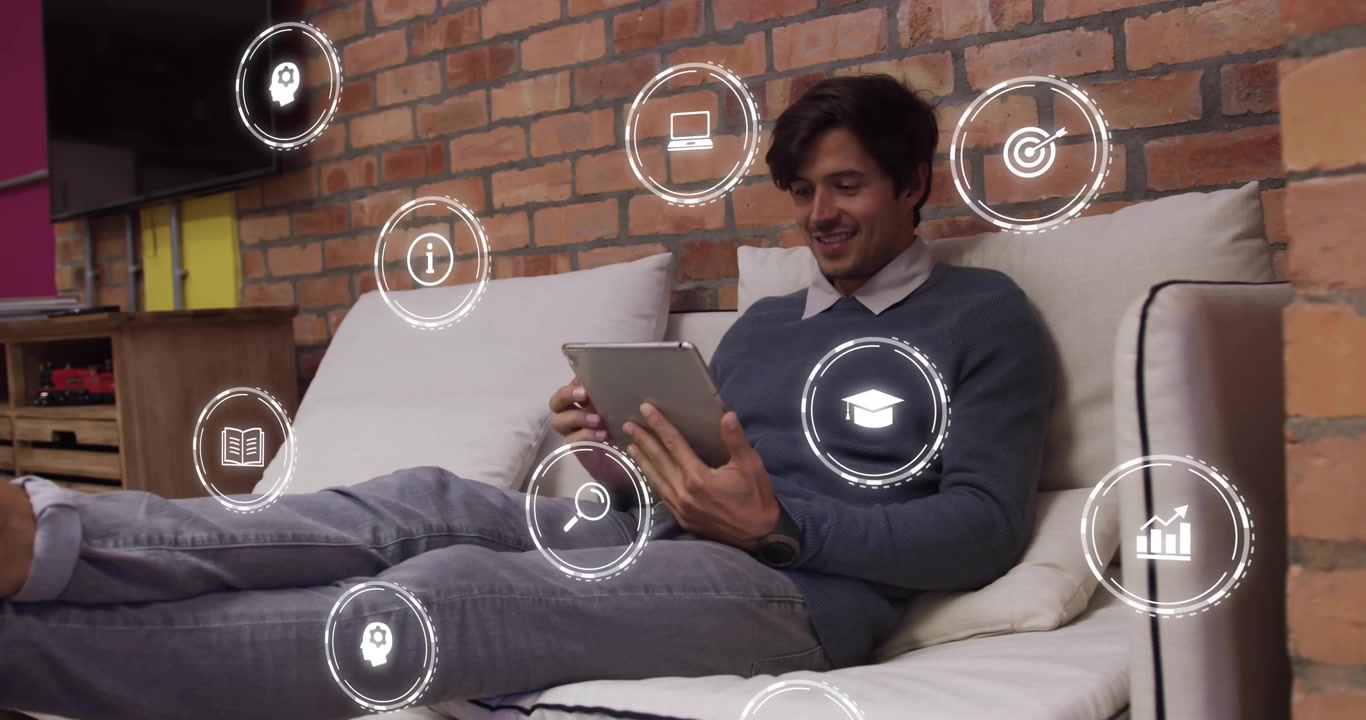 Man on couch tapping tablet, causing icons appearing around him, sitting, smiling, using tech app