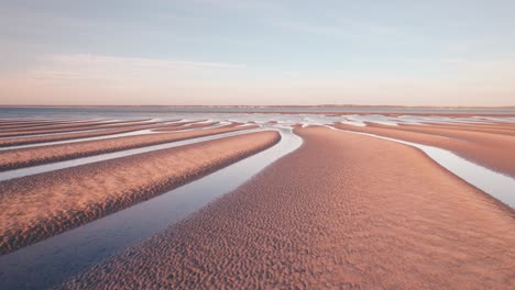 Hermosas-Dunas-De-Arena-Naranja-Dorada-Con-Líneas-Principales-Hacia-El-Horizonte-Del-Océano