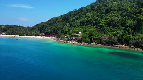 Island-Hill-Huts-in-lush-Jungle-fores,-emerald-waters-lagoon