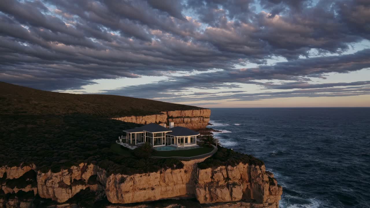 Luxury House on a Clifftop at Sunset with Dramatic Ocean Waves
