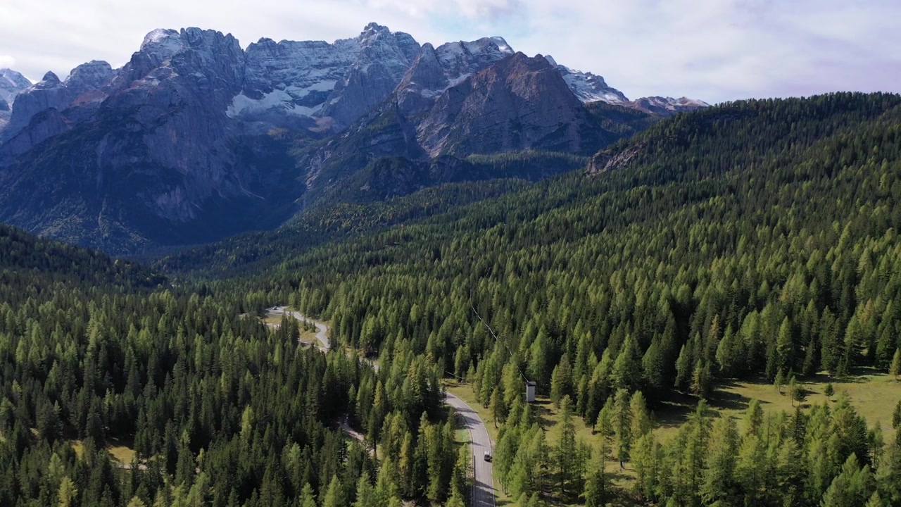 Betagende højvinkel droneoptagelse af den barske Monte Pelmo bjergtop i de italienske Dolomitter. Viser snedækkede klippeformationer, lave dal-skyer og varmt gyldent solnedgangslys.