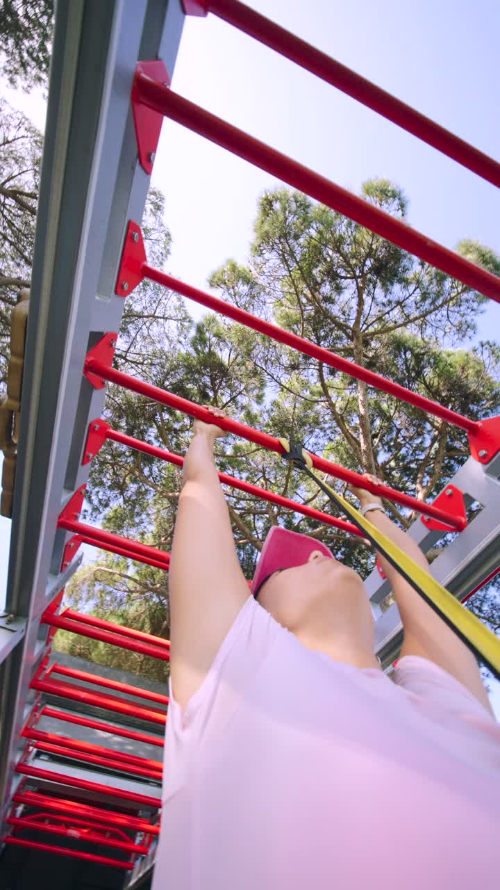 Woman doing pull-ups with resistance band at outdoor gym