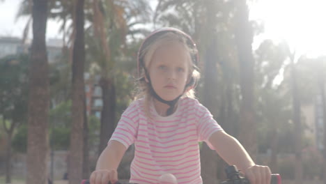 a young girl smiles while riding her bike in the park