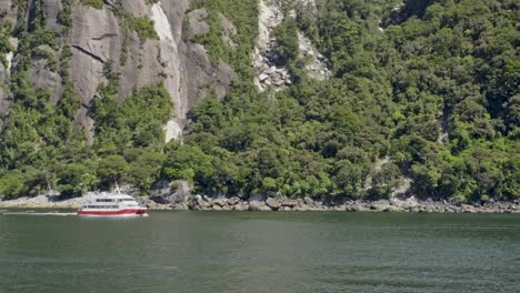 cruise sailing at milford sound with green trees in the mountain at fiordland, new zealand