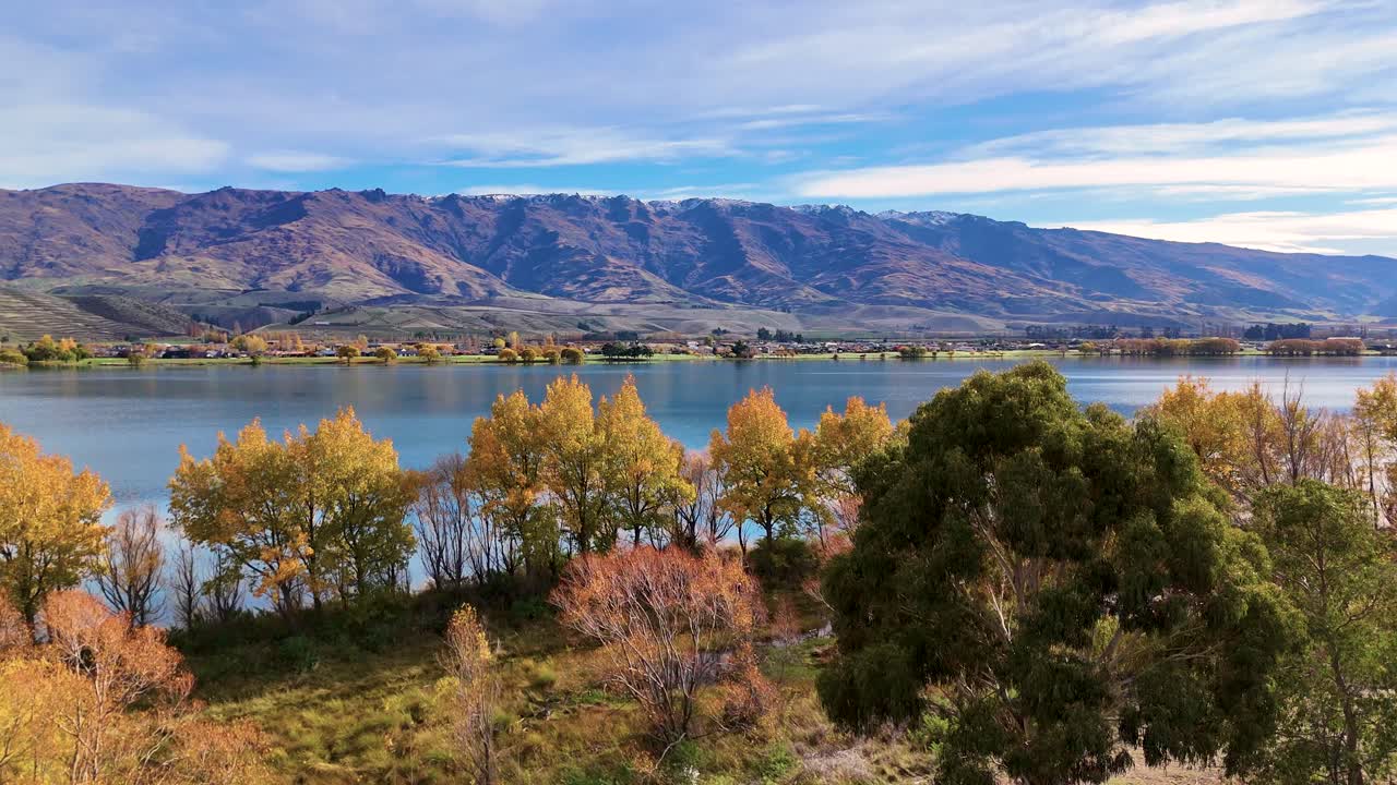 Aerial view of Lake Dunstan with vibrant autumn foliage and serene water reflections under a clear sky
