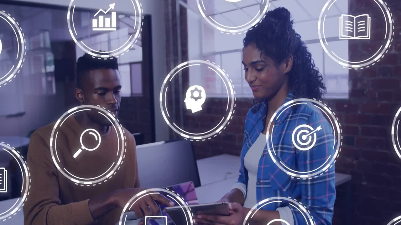 Co-workers using tablet and explaining business data while tapping screen, floating icons circling