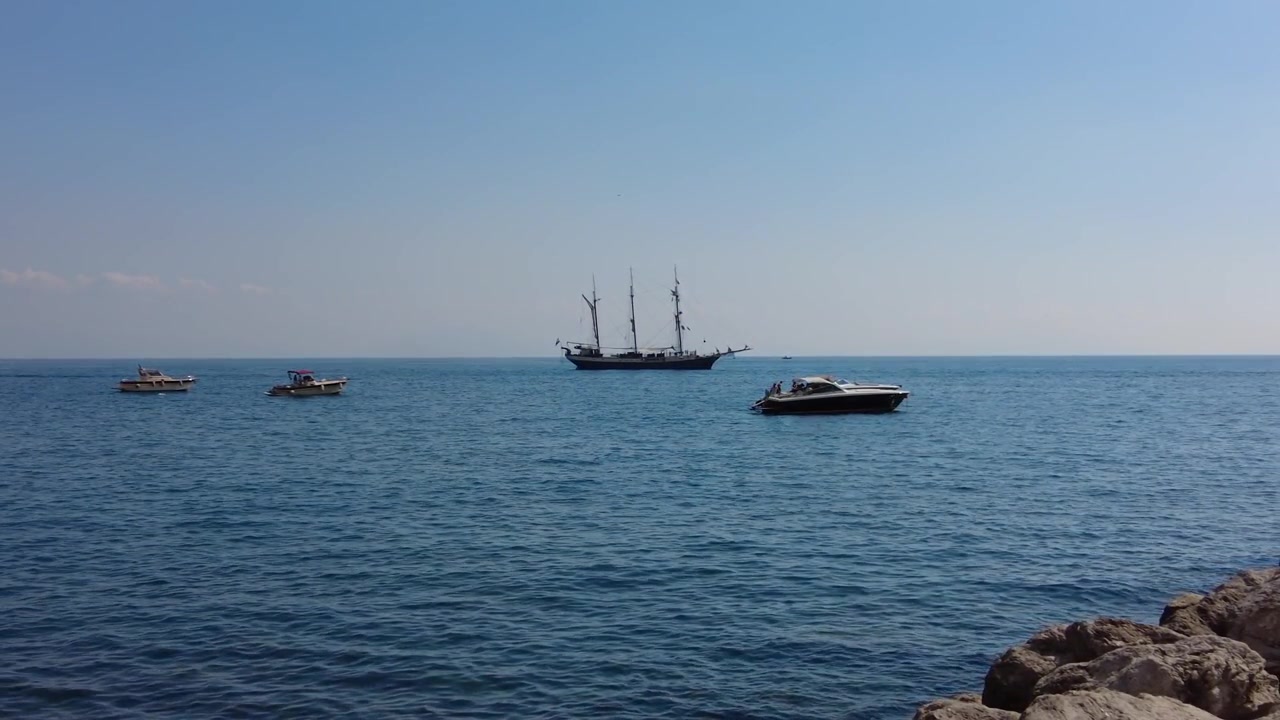Motoscafo e vecchia nave che galleggiano nel mare vicino alla Costiera Amalfitana in Italia. - Ampia.