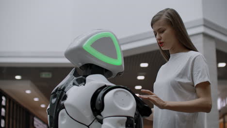 A-female-programmer-tests-the-robot-for-the-ability-to-interact-with-users.-The-use-of-a-robot-assistant-in-the-office.-The-robot-gives-help-to-the-girl