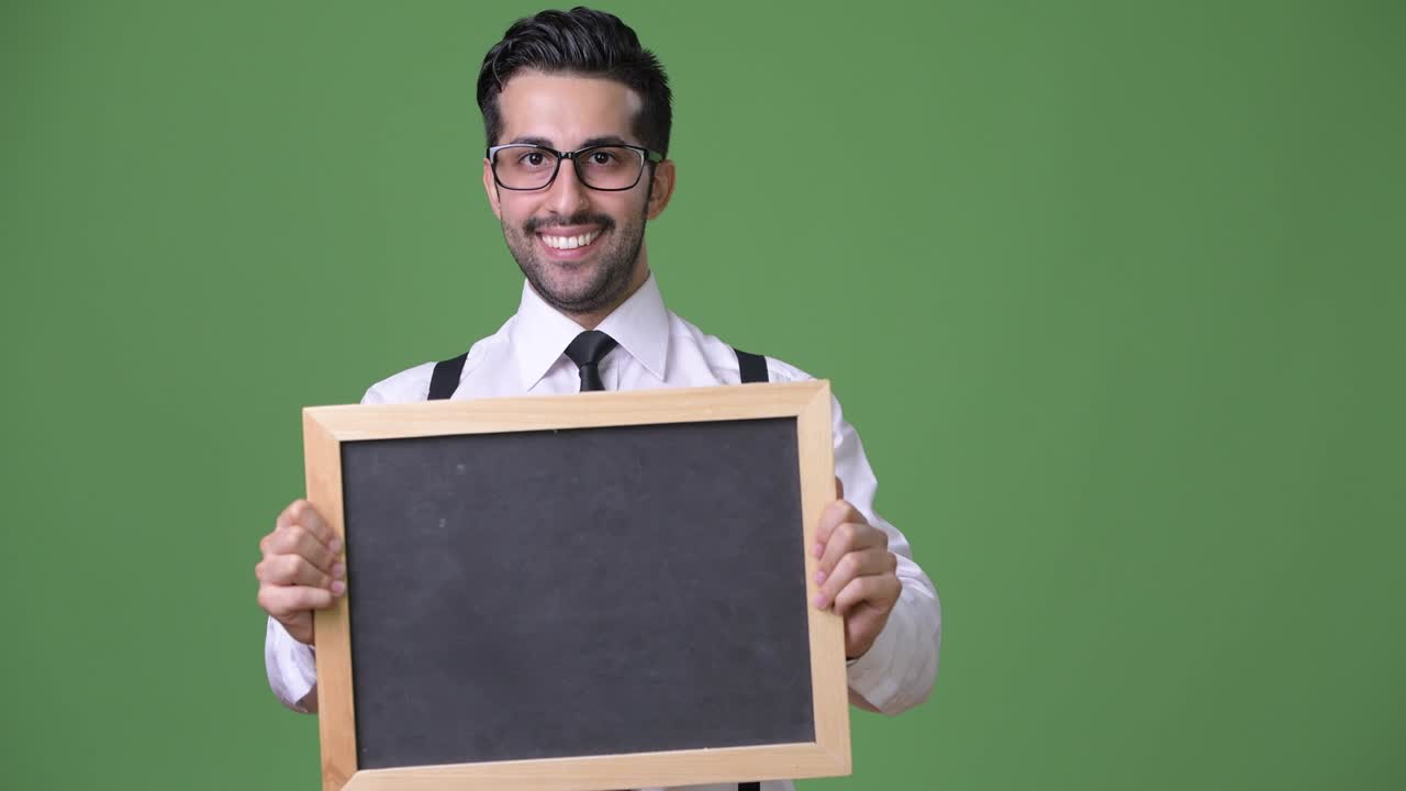 joven empresario persa barbudo y guapo contra un fondo verde