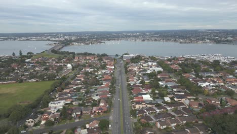 Autovía-Aérea-De-4k-O-Autopista-Dividida-En-El-Centro-Entre-Las-Casas,-Casas-Y-Propiedades-Del-Vecindario-Con-Drones-De-Tráfico-Volando-Hacia-La-Autopista-Sobre-El-Puente-De-Agua