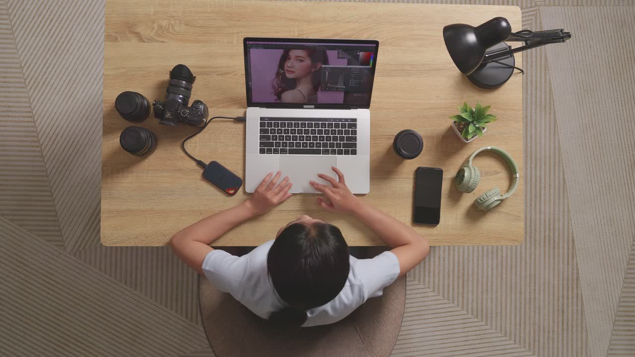 Top View Of Asian Woman Editor Thinking About The Idea While Sitting In The Workspace Using A Laptop Next To The Camera Editing Photo Of A Woman At Home