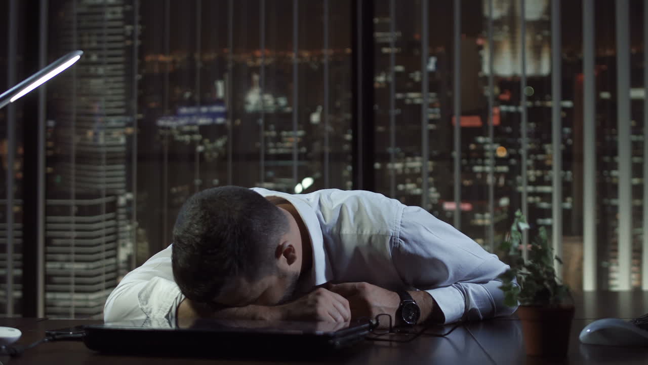 Exhausted Businessman Asleep on Desk in Office at Night