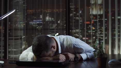 exhausted businessman asleep on desk in office at night
