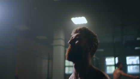 a powerful and strong athlete pushes dumbbells standing in the gym in slow motion.