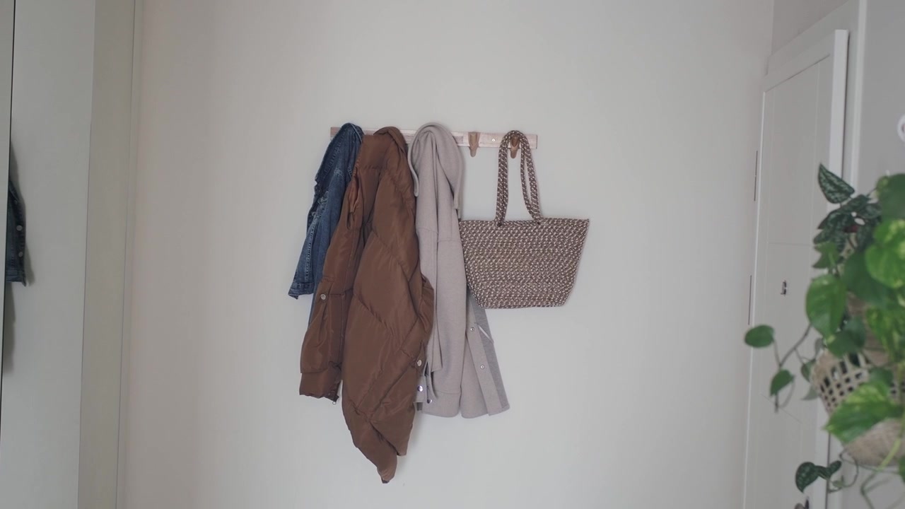 Abrigos y bolso tote colgados en un gancho de pared