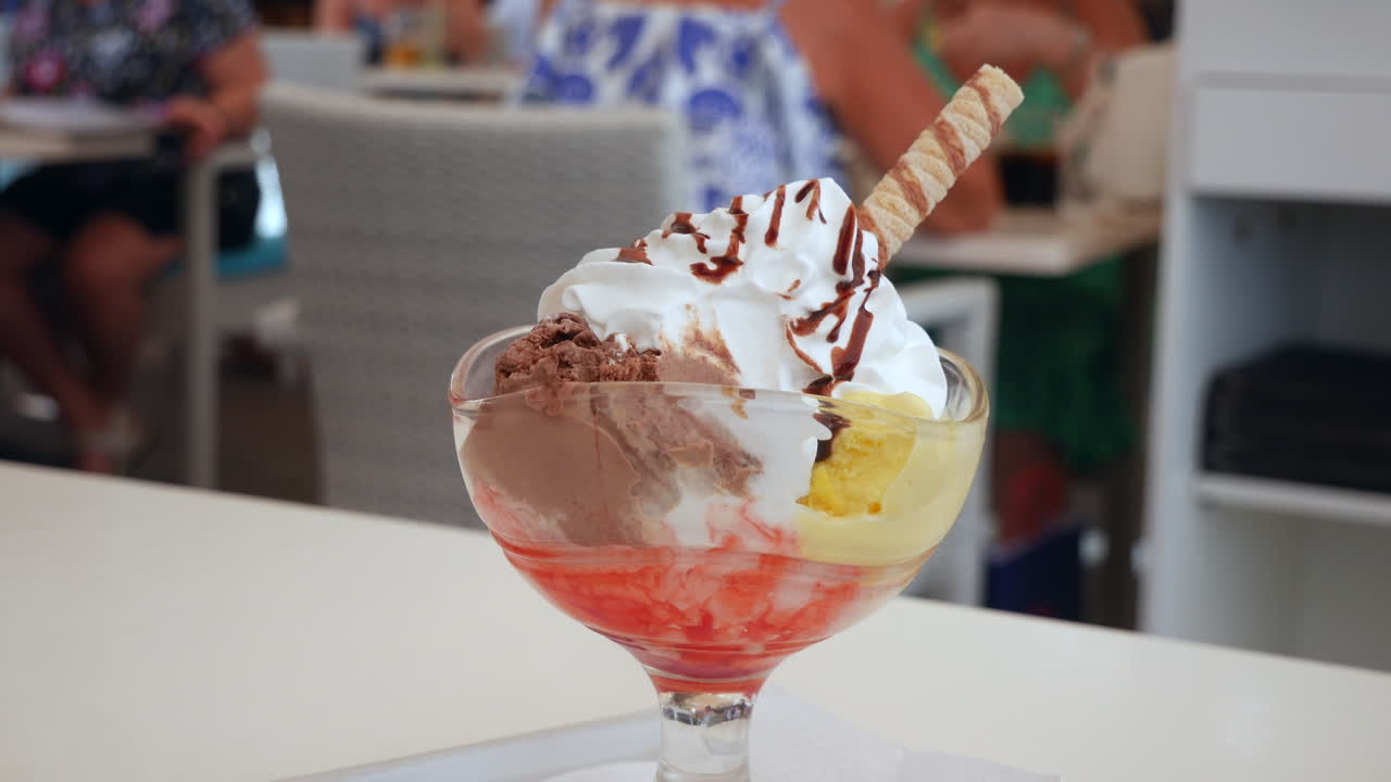 una mano se mete en un helado cremoso con chocolate en un café, molestando las papilas gustativas con una cuchara ideal para blogs de comida y marketing de postres