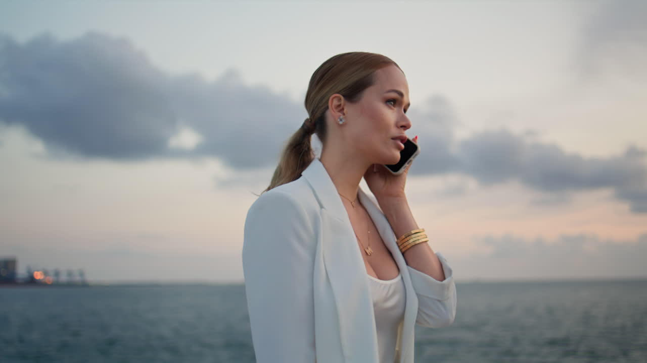 아름다운 해가 지는 곳에 서 있는 여성이 스마트폰으로 문제를 해결하고 있습니다.