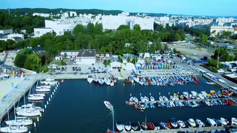 aerial trucking shot of marina with docking boats and cityscape of gdynia in background, poland