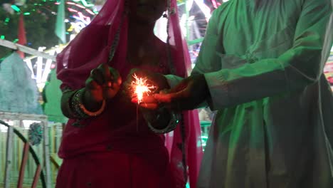 una pareja india en un vestido tradicional con una galleta brillante de fuego en el festival diwali mela en la india