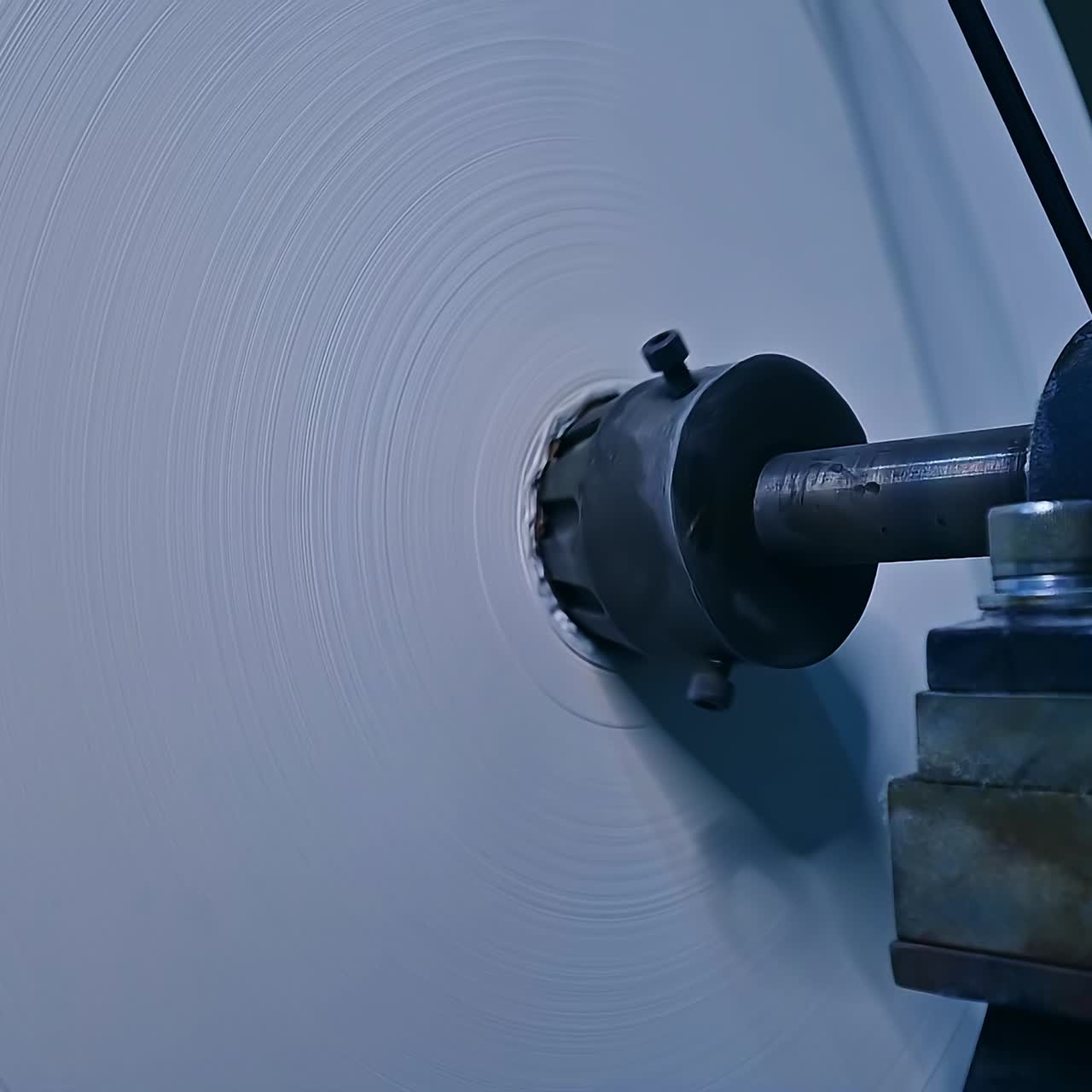 Enormous rotating roll of white ribbon. The reel of cloth used for the manufacturing of diapers at the factory. Close up