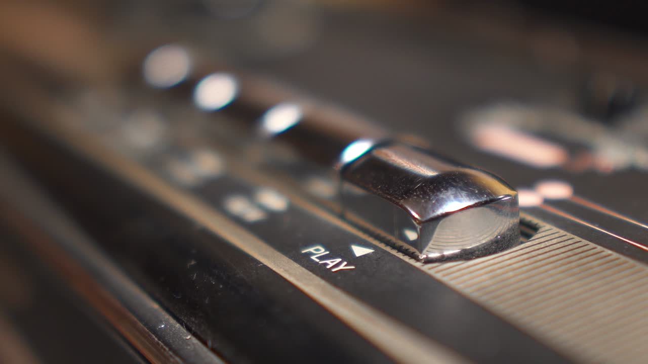 손가락이 테이프 레코더의 재생 버튼을 클로즈업으로 누르면