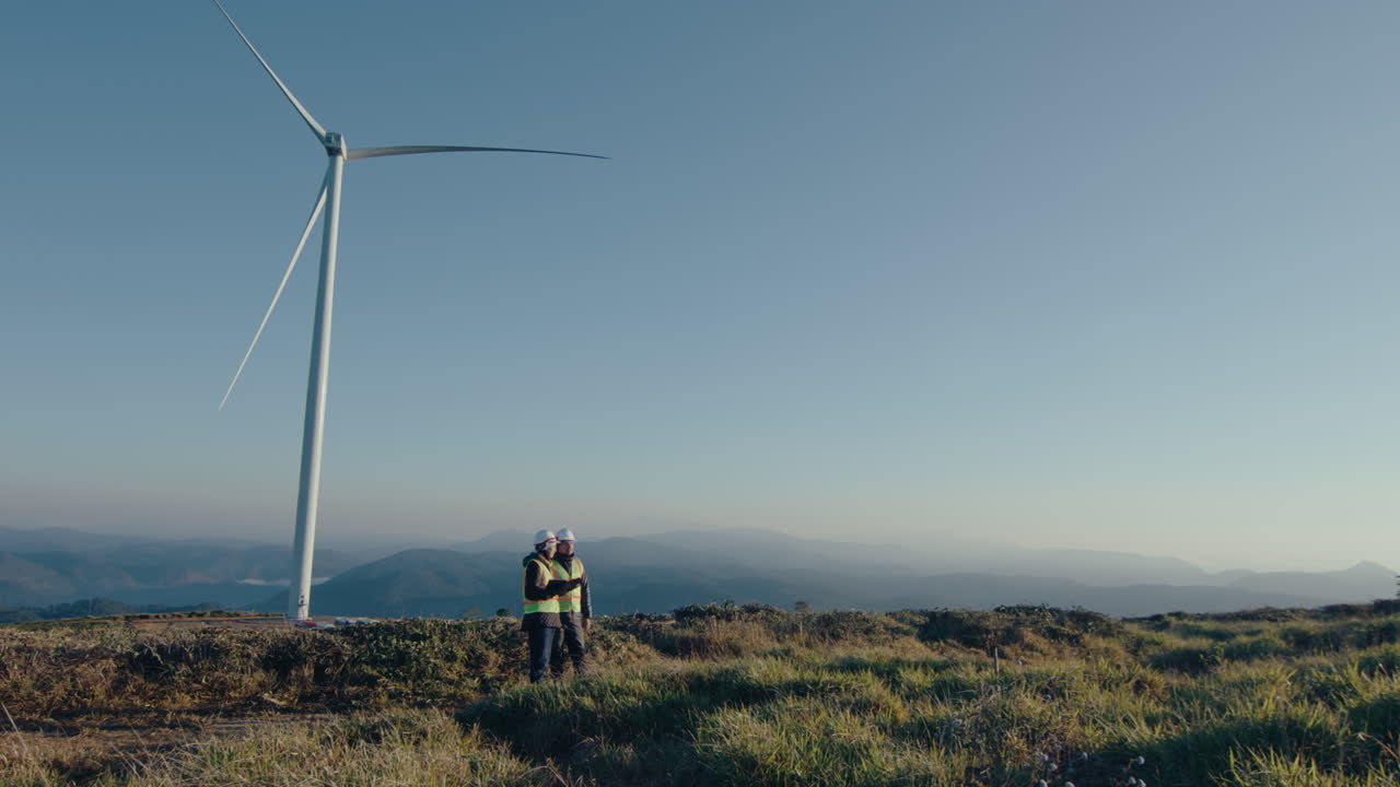 Two Engineers Discussing Maintenance of Wind Farm