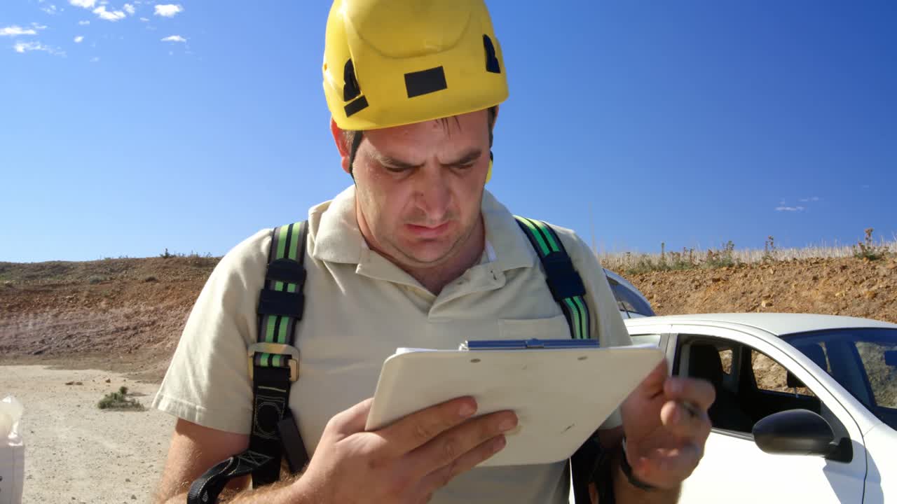 ingeniero masculino escribiendo en el clipboard en el parque eólico 4k