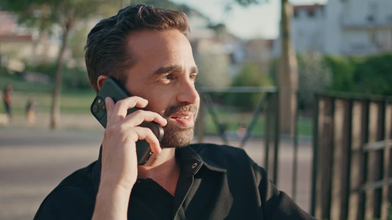 Calm man answering call at sunlight nature close up. Laughing guy talking phone