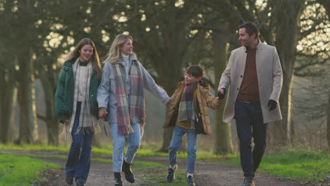 full length shot of family holding hands on walk through autumn countryside together - shot in slow motion