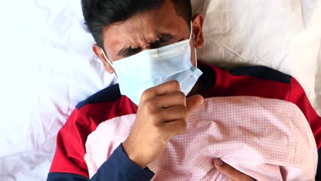 man coughing in bed with mask