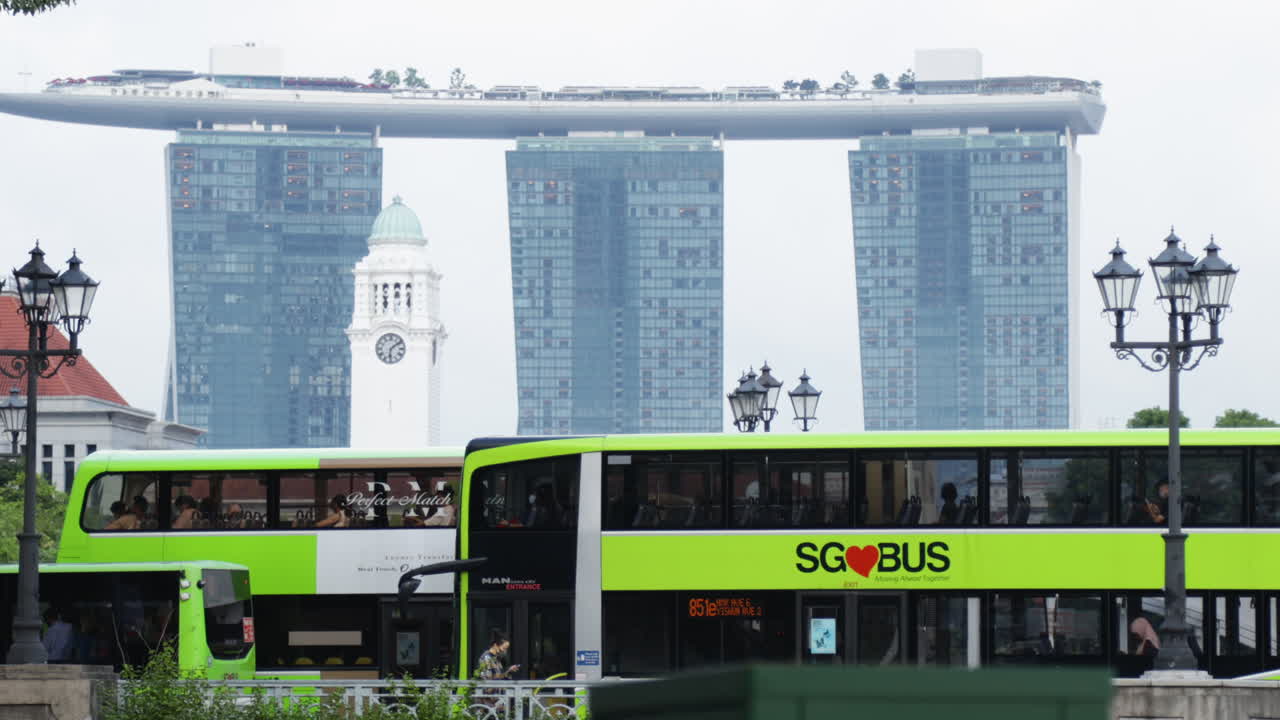 Green buses passing in front of Singapore’s iconic skyline with Marina Bay Sands in the background