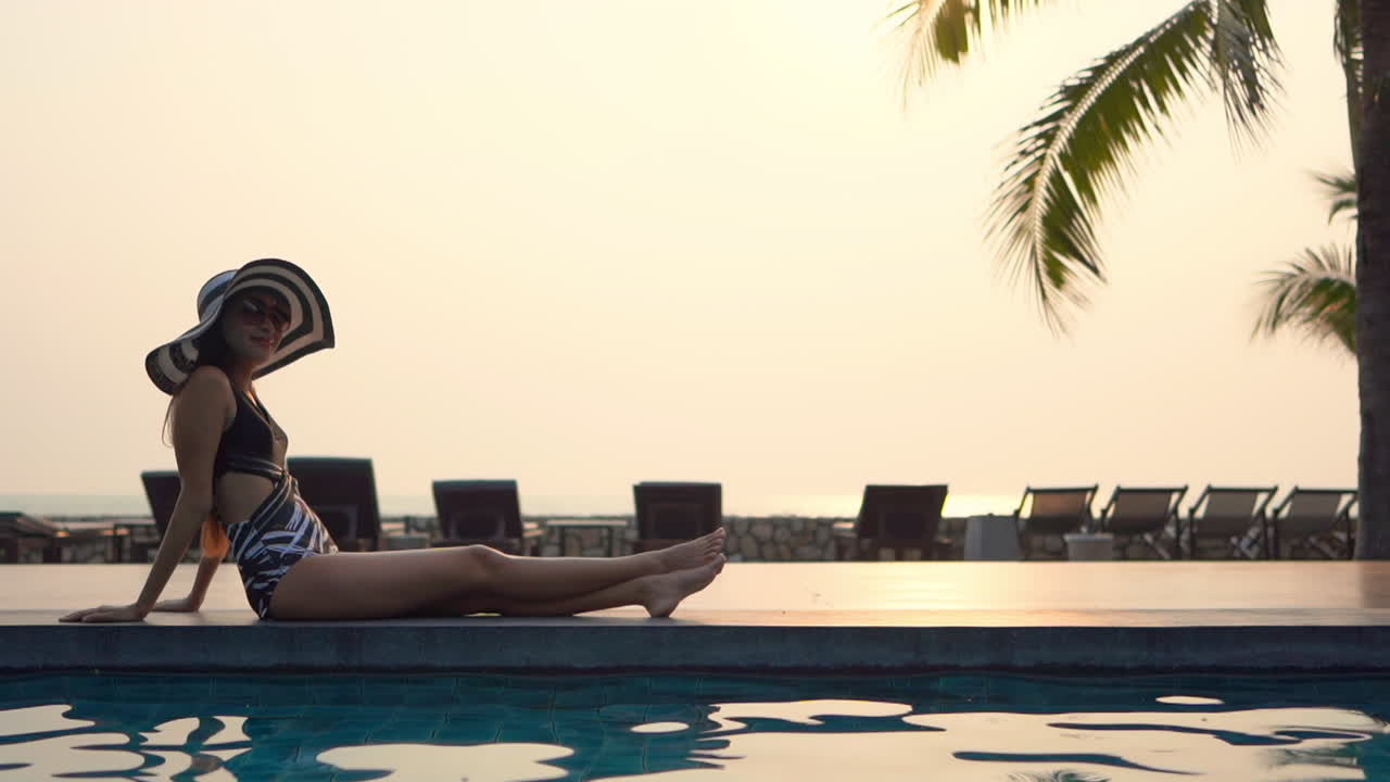 Relaxed woman enjoys vacation by pool on summer sunset, luxury resort