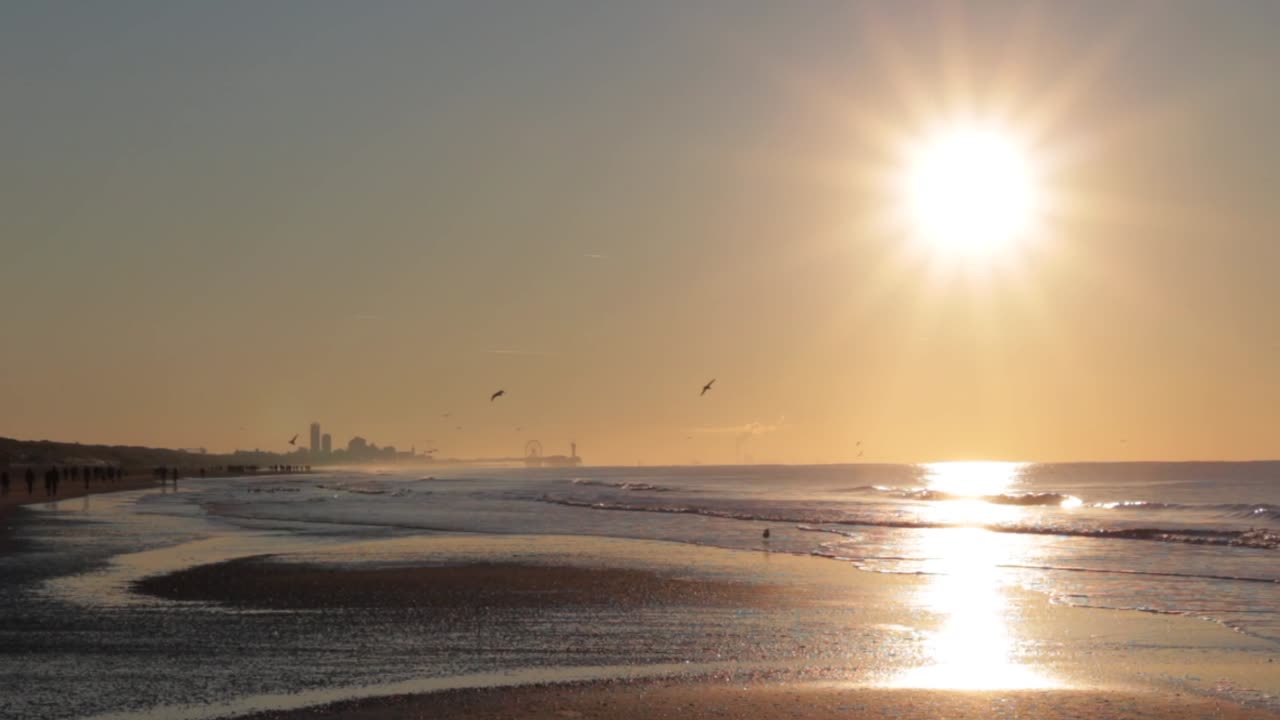 도시와 부두를 배경으로 햇볕이 잘 드는 해변을 걷는 사람들