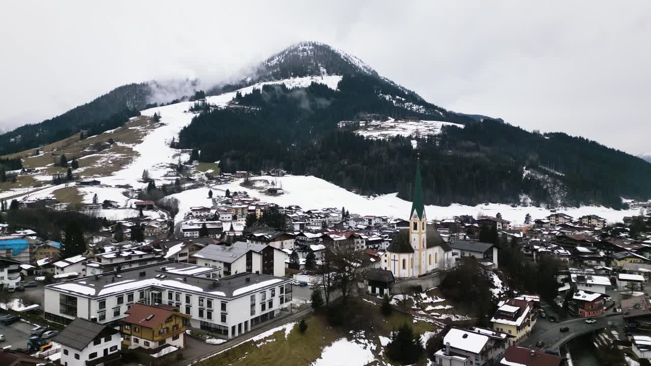 paisaje montañoso nevado y la pequeña ciudad de kirchberg, vista aérea de un dron