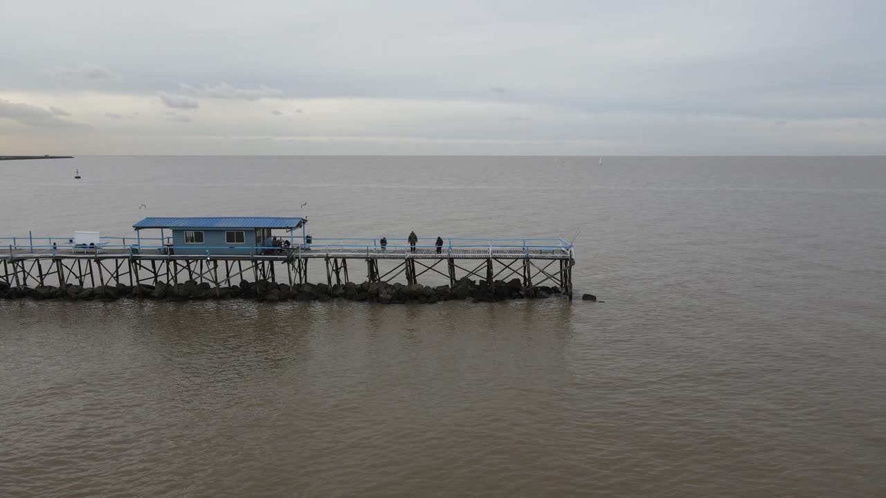Aerial view of people on long pier over water in the vast endless ocean