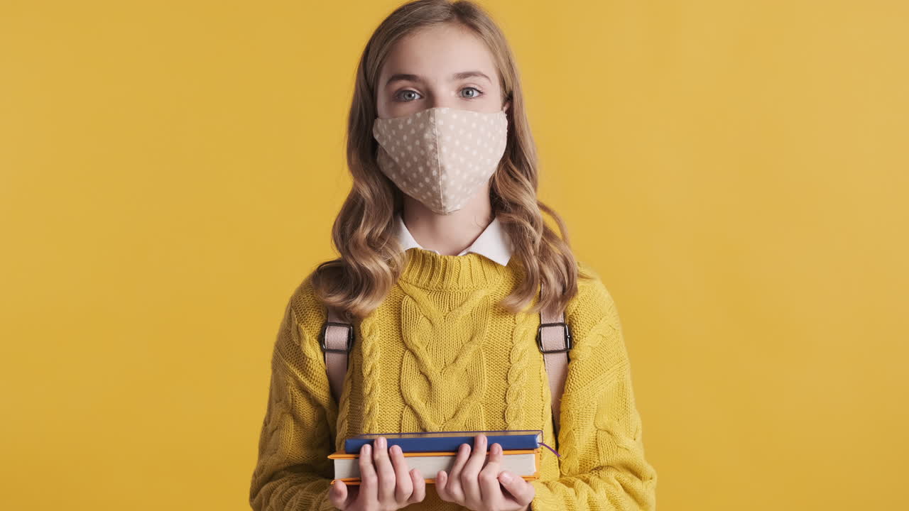 책 들고 있는 얼굴 마스크를 입은 십대 백인 소녀.