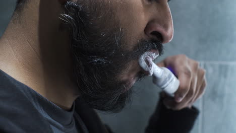 ethnic minority adult male using electric toothbrush