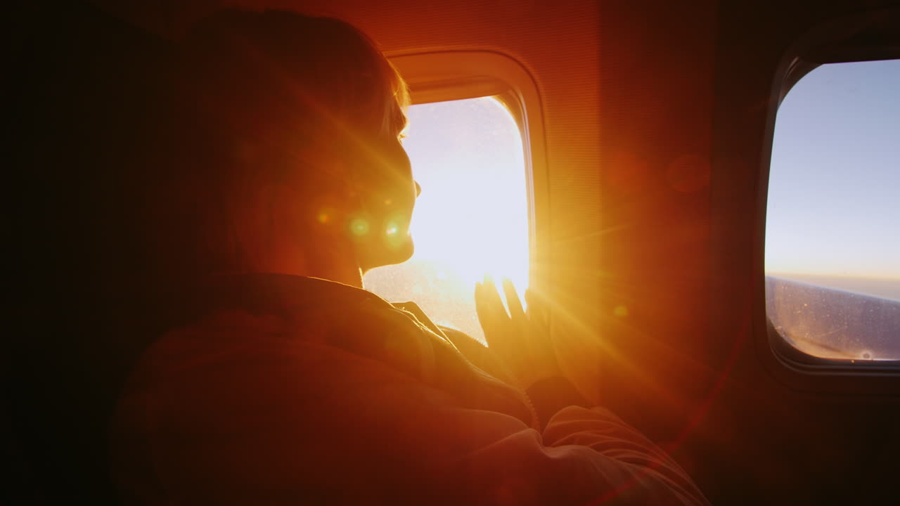 여객기 창문에서 태양을 바라보는 젊은 여성