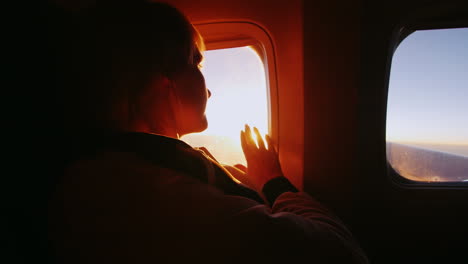 Mujer-Joven-Mirando-El-Sol-Desde-La-Ventana-De-Un-Avión.