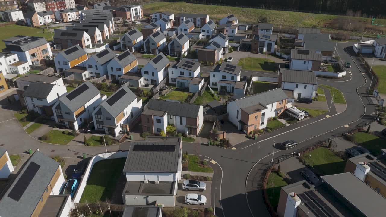 Aerial view of curved cul-de-sac of upscale homes with pitched roofs, solar installations, wide drives and landscaped plots conveying quiet sustainable neighborhood living