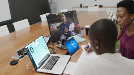 diverse businesswomen in office using computer with video call and ai messaging on screens